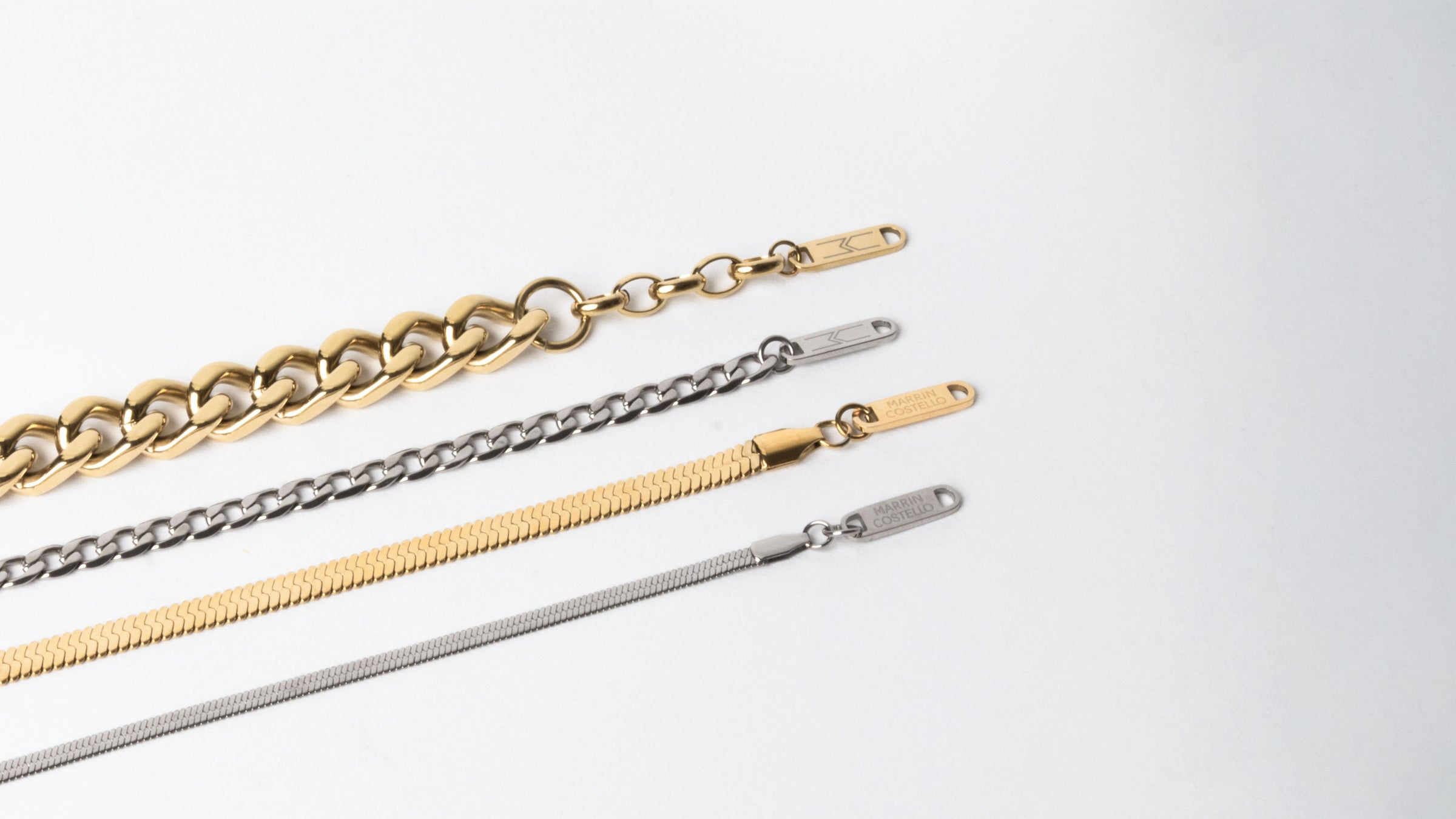 Anklets from the MARRIN COSTELLO jewelry collection, lined up to showcase the differences between the Queens, Callie, and Ramsey anklets. Available in 14k gold plated stainless steel and polished stainless steel.