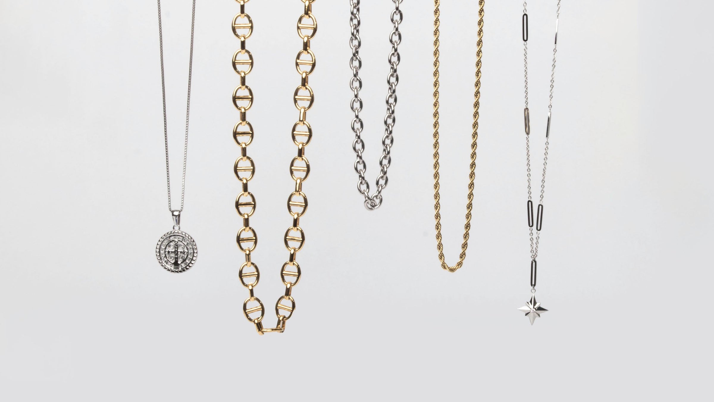 Necklaces from the MARRIN COSTELLO jewelry collection, hanging as if being worn, to showcase the different styles of necklaces. Available in both 14k gold plated stainless steel and polished stainless steel.