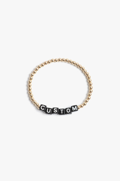 Marin Costello Jewelry Crown Letter Bracelet beaded block letter bracelet, customizable. Black block letters, gold beads. Waterproof, sustainable, hypoallergenic. 14k gold plated stainless steel.