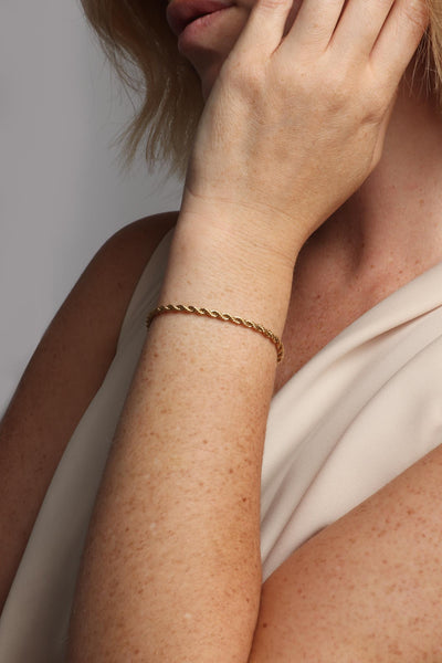 Marrin Costello wearing Marrin Costello Jewelry Helix 3mm rope twist chain bracelet with lobster clasp closure. Waterproof, sustainable, hypoallergenic. 14k gold plated stainless steel.