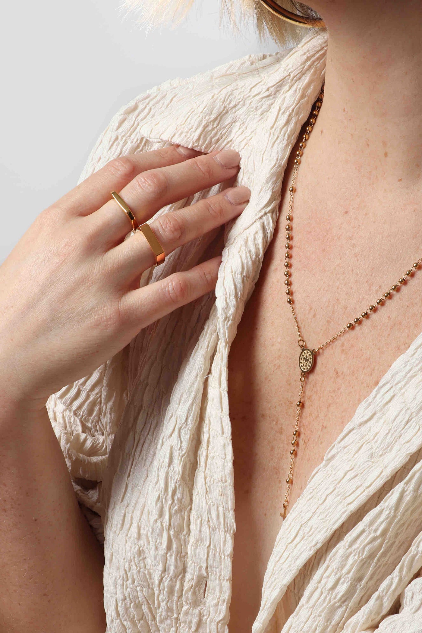 14k gold plated stainless steel water resistant and hypoallergenic layers of Marrin Costello Jewelry, featuring the hollow and comfortable everyday Michaela 3" large Hoops, functional and delicate 3mm beaded Ally Rosary in gold, geometric and signet Hendrix Stack ring set, and our famous herringbone Ramsey 5mm chain bracelet, paired with a textured ivory collared top from Canvas Fashion Gallery
