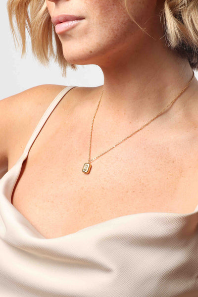 Marrin Costello wearing Marrin Costello Jewelry Orion Signet Pendant necklace with square pendant. Pendant is engraved with a star and CZ detail with spring ring clasp closure and extender. Waterproof, sustainable, hypoallergenic. 14k gold plated stainless steel.