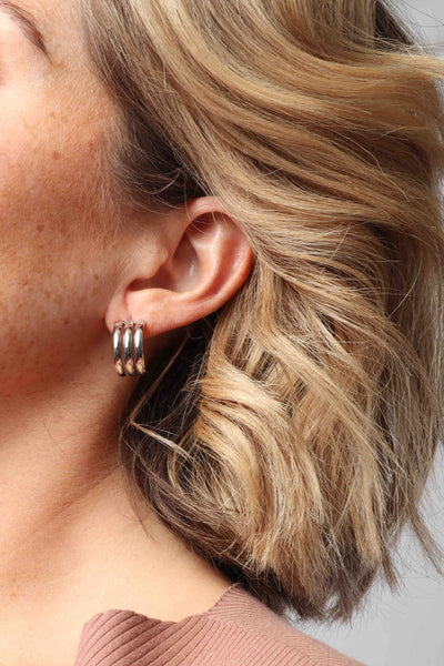 Marrin Costello wearing Marrin Costello Jewelry Petra Hoops triple ribbed post back earrings — for pierced ears. Waterproof, sustainable, hypoallergenic. Polished stainless steel.