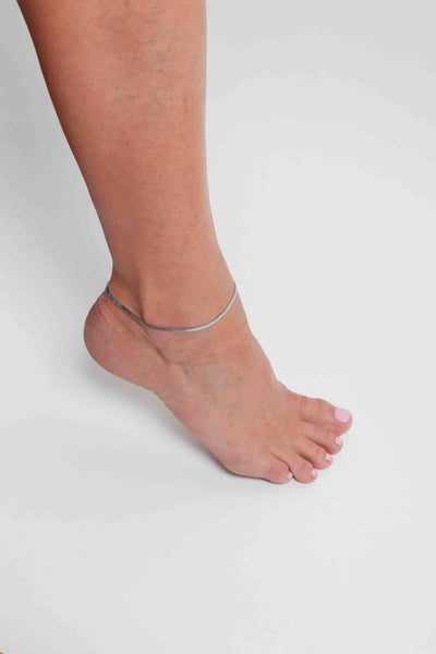 Marrin Costello wearing Marrin Costello Jewelry 3mm herringbone snake chain anklet with lobster clasp closure. Waterproof, sustainable, hypoallergenic. Polished stainless steel.