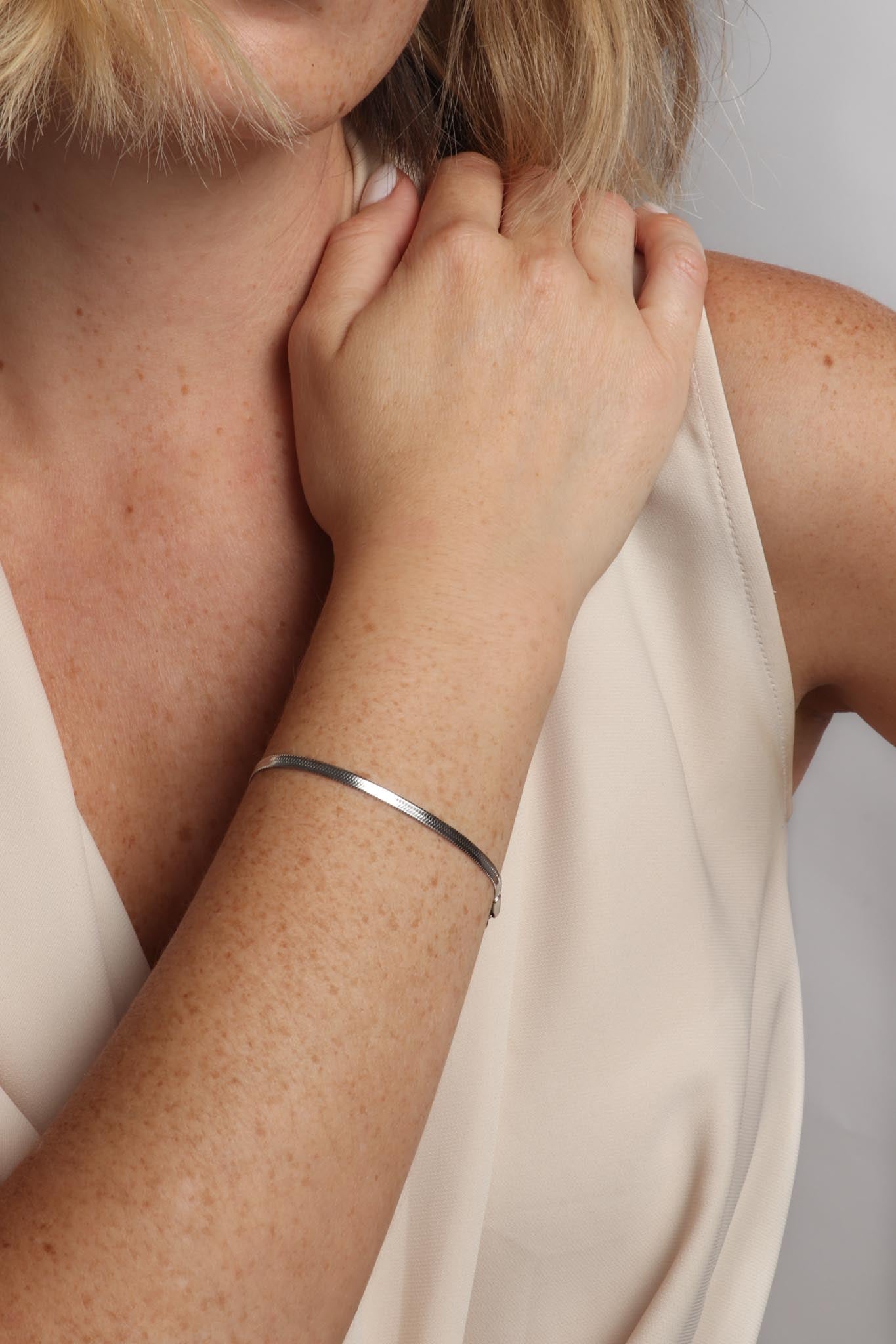 Marrin Costello wearing Marrin Costello Jewelry 3mm thick herringbone snake chain bracelet with lobster clasp closure. Waterproof, sustainable, hypoallergenic. Polished stainless steel.